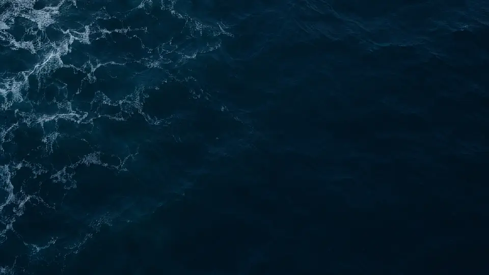 A deep navy sea seen from above, with white foam at one edge.